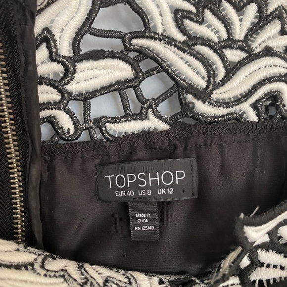 It’s a black and white off shoulder top with an embroidered flower design. - Picture 2 of 7